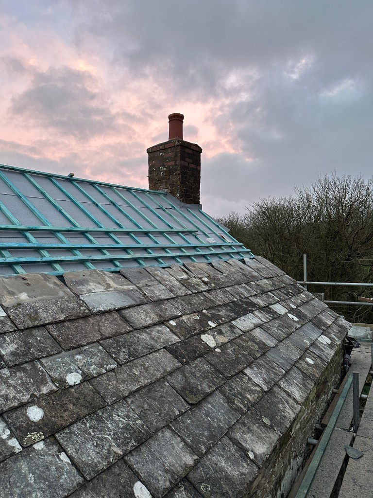 A partially completed section of roof work using Delabole slates