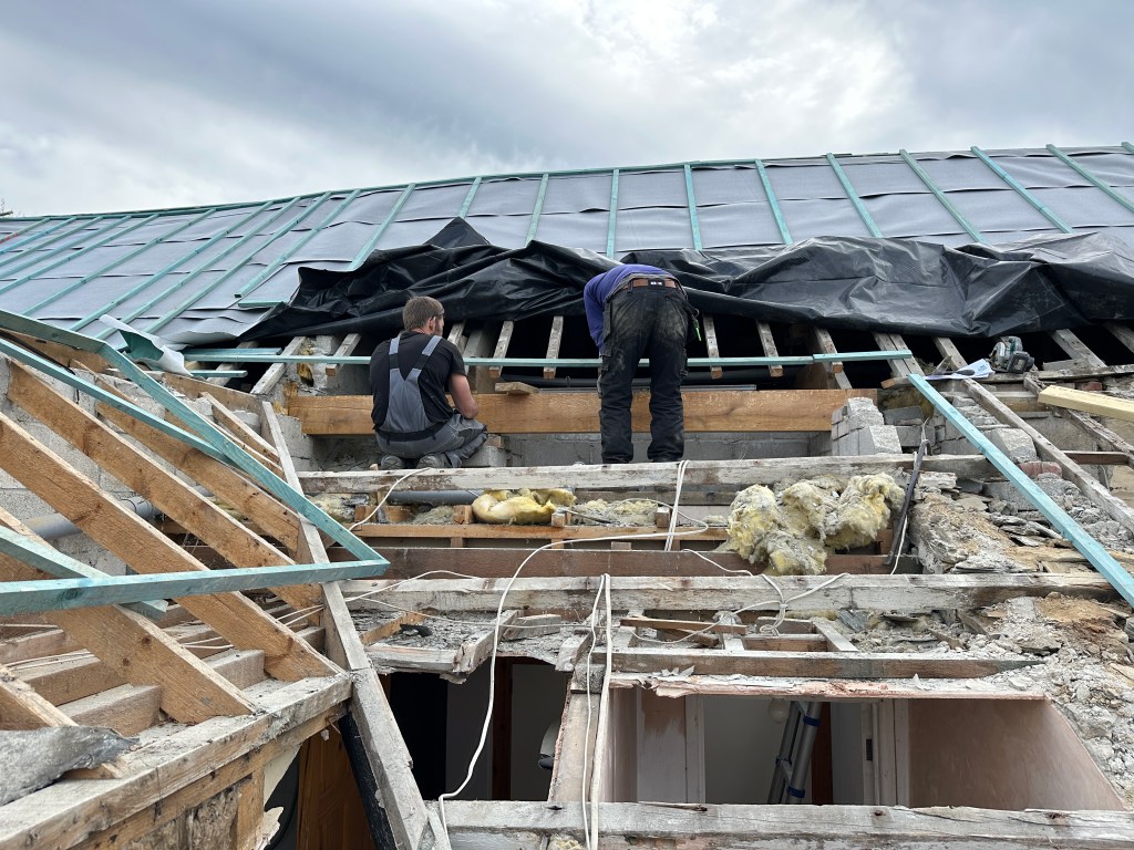 Roofers positioning a new beam inside an open roof structure