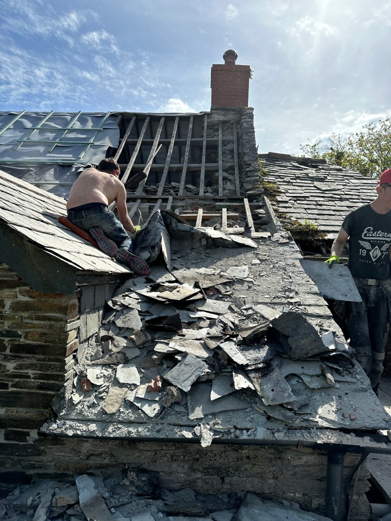 A section of roof during renovation, with messy and broken slates visible.